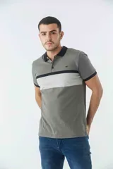 Remera tipo polo de manga corta con diseño de bloques de color en tonos verde oliva, gris y negro. Presenta cuello y puños a contratono, cierre frontal con botones y logo bordado en el pecho.