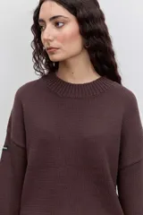 Sweater de punto en color beige, con cuello redondo acanalado, mangas largas con puños ajustados y diseño holgado.