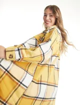 Sobrecamisa larga de tejido soft con estampado de cuadros en tonos celestes, beige y blanco. Presenta cuello con solapa, cierre frontal con botones, bolsillos aplicados en el pecho y mangas largas con puños abotonados.