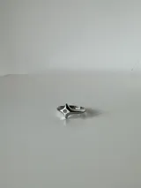Anillo de acero quirúrgico con diseño de estrella de cuatro puntas y un pequeño cristal incrustado en el centro.