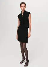Top negro de tweed sin mangas, con escote en V, diseño cruzado y terminaciones deshilachadas.