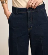 Pantalón de jeans azul oscuro, de corte ancho y cintura alta, con trabillas en la cintura y friso delantero.