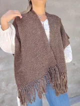 Ruana tejida color marrón con flecos en el ruedo.