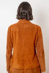 Blazer de gamuza color chocolate, con cuello camisero, cierre frontal de botones claros y corte recto.