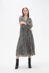 Vestido midi de corte evasé con estampado animal print en tonos oscuros. Presenta escote en V cruzado, mangas largas con puños y falda con volados escalonados.