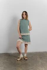 Conjunto de top sin mangas y minifalda a rayas color verde agua y blanco, con flecos en el ruedo. Tejido confeccionado en Uruguay con 50% poliéster y 50% algodón.