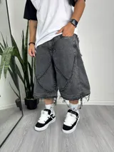 Pantalón baggy desmontable de denim gris oscuro con diseño patchwork y terminaciones desflecadas.