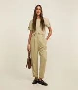 Pantalón zanahoria de cintura alta color beige, confeccionado en tejido piqué con viscosa sostenible. Cuenta con cierre tradicional, cintas con botones en la cintura, pliegues y dobladillo en el bajo.