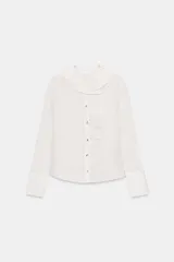 Camisa de manga larga con estampado de rayas verticales finas, cuello redondo con volante plisado y detalle de volante lateral en el frente. Cuenta con cierre frontal de botones y puños anchos.