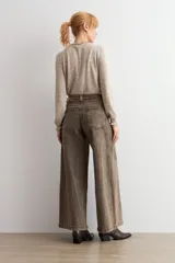 Jean culotte de tiro alto y corte ancho, color marrón chocolate con efecto lavado. Presenta costuras verticales frontales, bolsillos laterales y cierre con botón y cremallera.