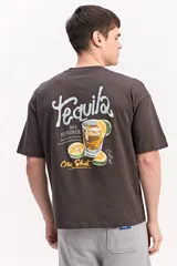 Remera boxy marrón oscuro de algodón con silueta amplia y corta, y estampado gráfico en la espalda con temática de tequila y limones.