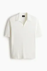 Remera polo de manga corta en punto trenzado suave, color blanco, con cuello abierto y remate acanalado en mangas y bajo.