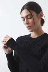 Sweater de tejido tipo rib, color negro, con cuello redondo y mangas largas. Presenta una textura acanalada y un ajuste al cuerpo.