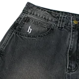 Pantalón jean baggy de denim color gris oscuro con lavado localizado, tiro medio y calce suelto. Presenta bordados en el bolsillo pequeño delantero y en los bolsillos traseros.