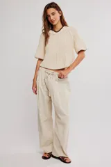 Pantalon de lino y algodon color beige, de tiro bajo, estilo relajado con cintura elastizada ajustable mediante cordón y bolsillos laterales.