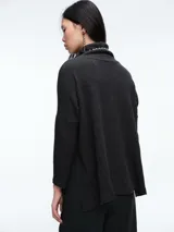 Buzo tejido de cuello alto, con diseño de sisa caída y silueta holgada. Presenta aberturas laterales en el ruedo que aportan movimiento.