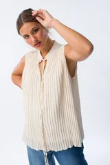 Blusa blanca sin mangas con cuello mao y pliegues verticales.