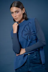Chaleco de lana color azul, con diseño de flor bordada en el frente y aberturas laterales en el ruedo.