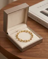 Pulsera de acero con baño de oro, compuesta por eslabones rectangulares unidos por esferas metálicas.