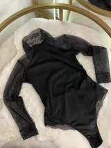 Body negro de terciopelo con mangas largas de tul y detalles de encaje en puños y parte inferior.