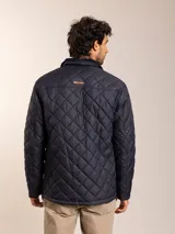 Campera acolchada azul marino con cuello de pana, cierre frontal con cremallera y bolsillos con solapa en el pecho.
