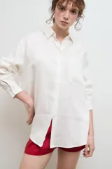 Camisa oversize de lino en color crudo, con cuello clásico, cierre frontal de botones y un bolsillo aplicado en el pecho.