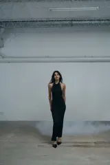 Vestido largo negro de corte ajustado, con espalda descubierta y detalle de tachas metálicas en los laterales. Presenta un tajo lateral en la falda.