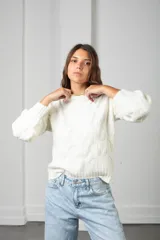 Sweater de punto color blanco, con cuello redondo y diseño de textura trenzada en relieve. Presenta mangas largas con puños ajustados y corte clásico.