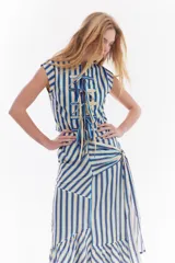 Blusa sin mangas de algodón con estampado de rayas en tonos beige, azul y rojo. Presenta diseño de inspiración oriental con cierre frontal de múltiples lazos para atar.