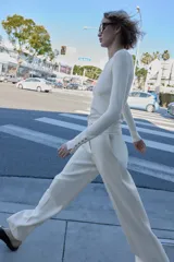 Pantalón blanco de tiro alto con pernera recta y pinzas marcadas en el frente. Cierre frontal con botón metálico dorado.