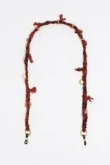 Cadena para lentes de tejido paisley en tonos rojo y negro, con detalles de nudos y cuentas doradas.