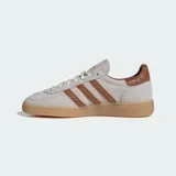 Championes Adidas Handball Spezial de diseño clásico, confeccionados en gamuza color beige con las icónicas tres tiras y refuerzo en el talón con textura de piel de serpiente en tono marrón. Presentan suela de goma color caramelo y detalles dorados en el lateral y la lengüeta.