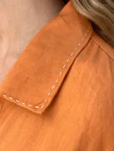 Vestido camisero largo color verde lima, con cuello camisero, mangas largas con puños abotonados, cierre frontal con botones y lazo anudado en la cintura.