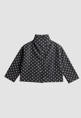 Campera de algodón con estampado de lunares blancos sobre fondo negro. Presenta cuello alto, cierre frontal con botones metálicos y cinturón ajustable en la cintura. Posee bolsillos laterales y un diseño versátil que permite llevarla entallada o con silueta holgada.