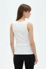 Musculosa de algodón color blanco, con tirantes anchos, escote en V cruzado y diseño asimétrico de canalé.