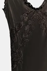 Vestido largo de viscosa en color negro, con escote redondo y tirantes anchos con detalle de volados. Presenta bordados florales a tono en la parte superior y bajo con terminación evasé.