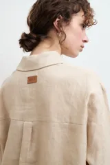 Camisa oversize de lino, color tostado, con cuello clásico, cierre frontal de botones y bolsillo en el pecho.