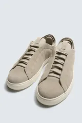 Zapatilla urbana de hombre confeccionada en piel con acabado de serraje, diseño minimalista con cordonera oculta y suela de goma a contraste.