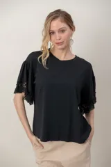 Remera de algodón negra, de corte holgado, con cuello redondo y mangas cortas abullonadas con detalles de encaje broderie.