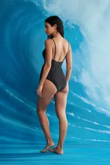 Trikini negro de una pieza con escote cruzado y lazo ajustable a la cintura que genera un corte cut-out en el abdomen. Posee delgados tirantes ajustables.