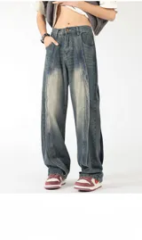 Pantalón de jean azul con efecto gastado y drapeados laterales que generan una abertura o pliegue vertical. Corte ancho y holgado.