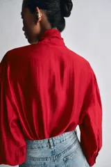 Camisa de ZARA Woman Collection confeccionada en hilatura con mezcla de lyocell, de color blanco marfil. Presenta cuello redondo, escote en V con lazadas en el mismo tejido, manga larga con puño y bajo recto.