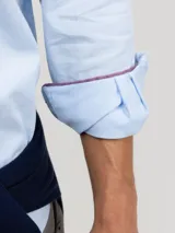 Camisa celeste a rayas verticales, de corte regular fit, cuello button-down, manga larga con puños abotonados y logo bordado en el pecho.