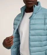 Campera puffer ultraligera de cuello alto con cierre frontal por cremallera y bolsillos laterales. Diseño acolchado con acabado liso.