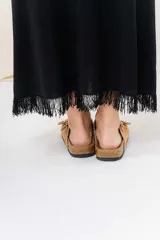 Vestido midi de tejido tipo seda con caída fluida, escote redondo y sin mangas. Presenta un diseño minimalista con detalle de flecos en el ruedo.