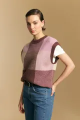 Chaleco tejido de punto con diseño de bloques a cuadros en tonos rosados, marrones y beige. Presenta cuello redondo y terminaciones acanaladas en cuello y sisas.