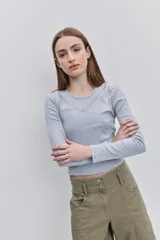 Remera de manga larga de tejido acanalado gris, con escote redondo y detalle de puntilla en el cuello.