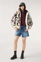 Campera bomber reversible con un lado de corderito estampado con manchas abstractas en tonos negro, marrón, azul y violeta sobre fondo blanco, y del otro lado liso en tono crudo.