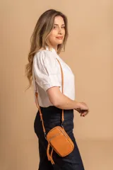 Bandolera compacta color rosado, con correa regulable y desmontable. Tiene apertura superior, bolsillo frontal con cierre y detalle de borla, y bolsillo trasero sin cierre. El interior está forrado en tela y cuenta con un bolsillo adicional.