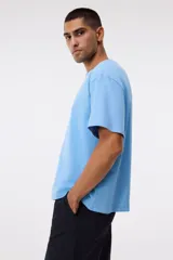 Remera de algodón celeste de corte relajado, con cuello redondo ribeteado y mangas cortas con hombros caídos.